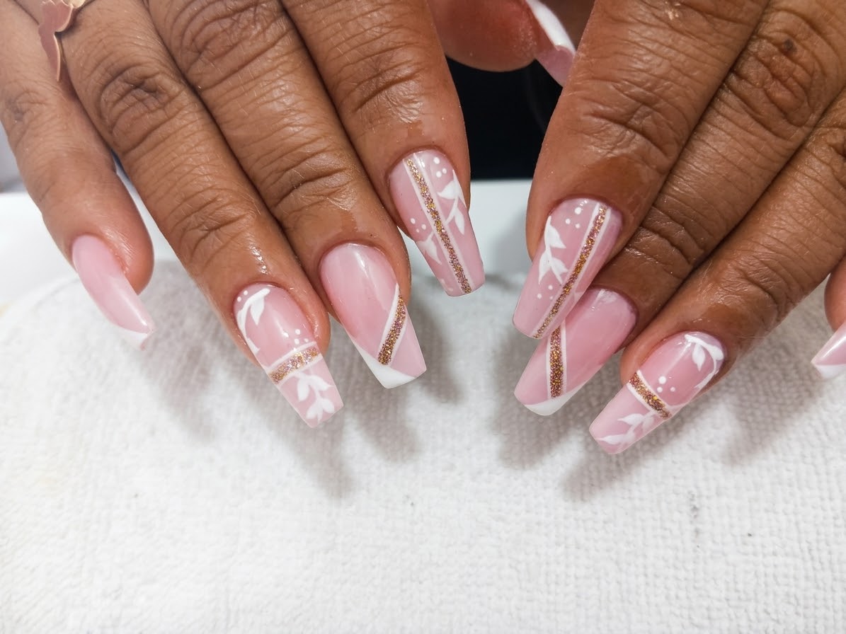 Uñas rosadas con diseño blanco y brillo dorado